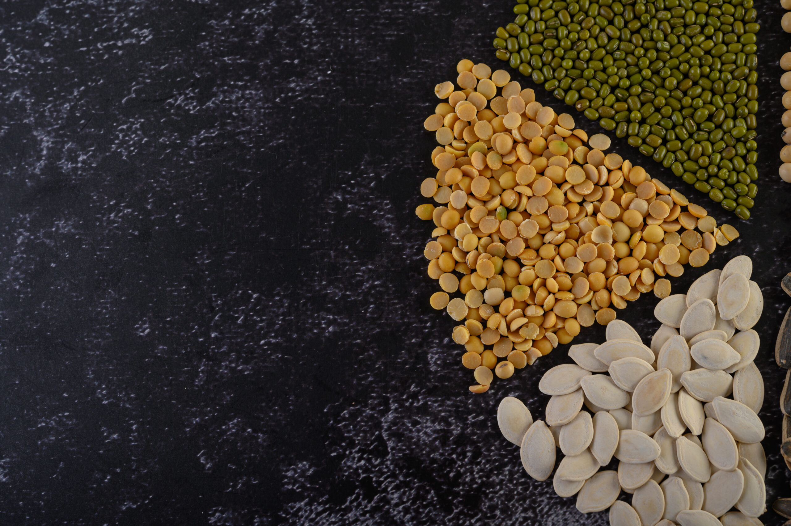 Legumes arranged in a circle on the black cement floor.